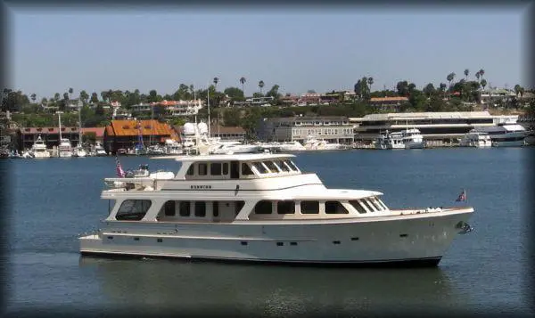 A large white boat in the water near some buildings.